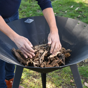 Mains disposant du bois de grillade Neandertal dans un brasero